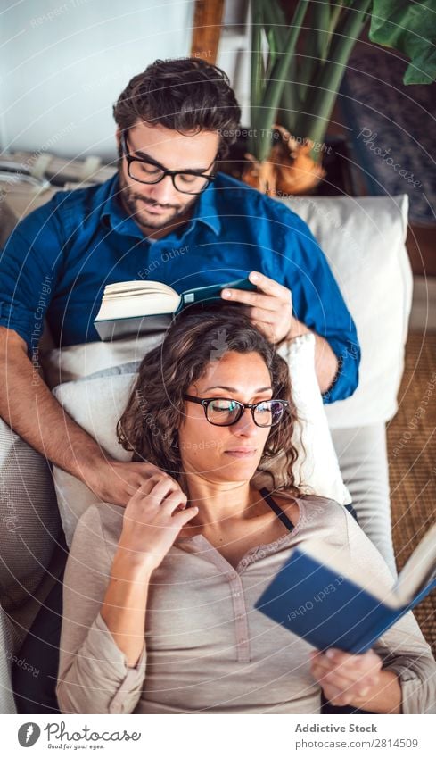 Junges Paar liest Buch auf der Couch zu Hause heimwärts Literatur Sofa Freizeit & Hobby Nähe attraktiv Jeansstoff Aussicht sitzen Tag Leben Erwachsene Zuneigung