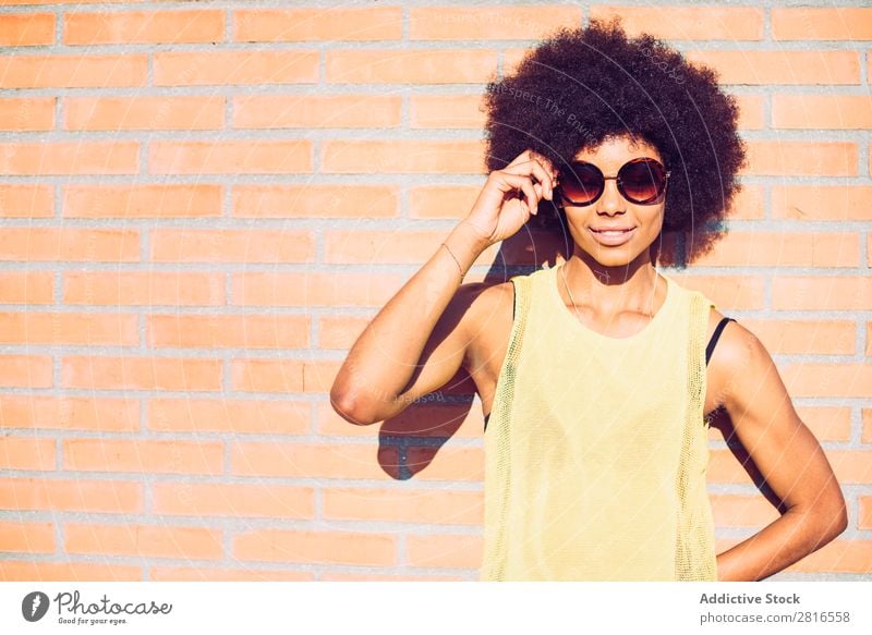 Junge schöne afroamerikanische Frau, die posiert und lächelt, während sie an der Ziegelwand steht. Afrikanisch Amerikaner charmant Backstein Model Hand