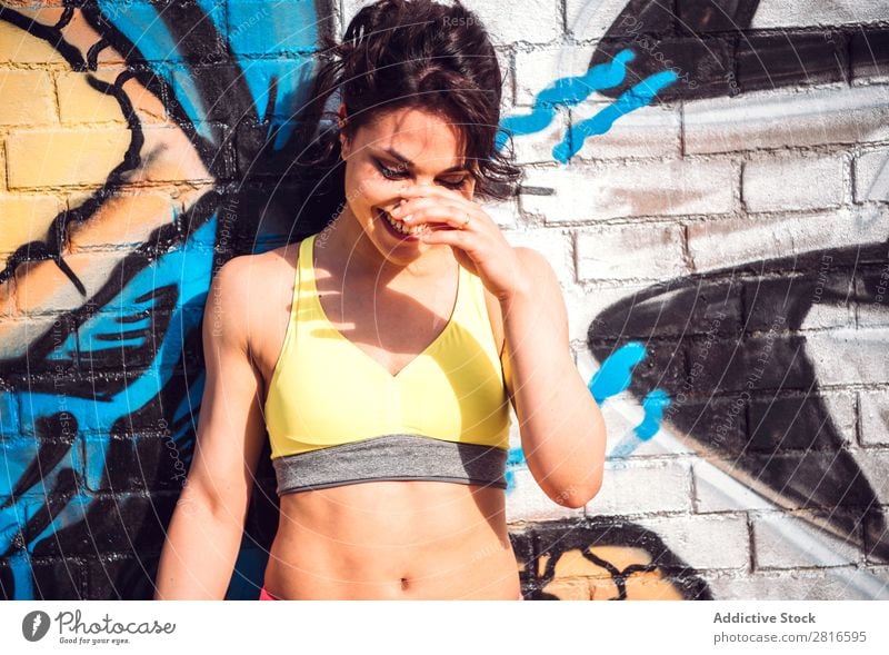 Sportliche Frau posiert in der Nähe der Stadtmauer Grafitti Graffiti Wand Bekleidung Freude Erwachsene Mensch Körperhaltung Jugendliche Mädchen Gesicht Farbe