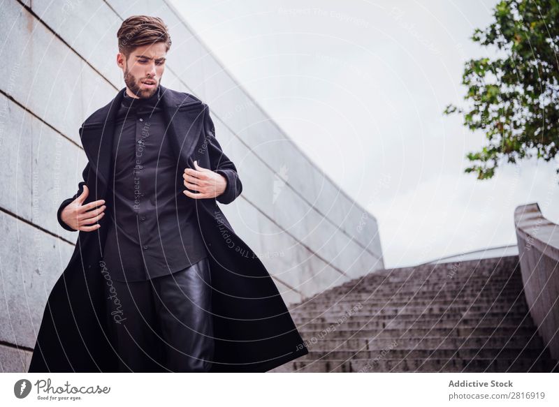 Junger, gutaussehender, trendiger Mann mit Mantel, der auf der Treppe posiert. Erwachsene attraktiv Vollbart bärtig lässig Kaukasier Coolness niedlich tief