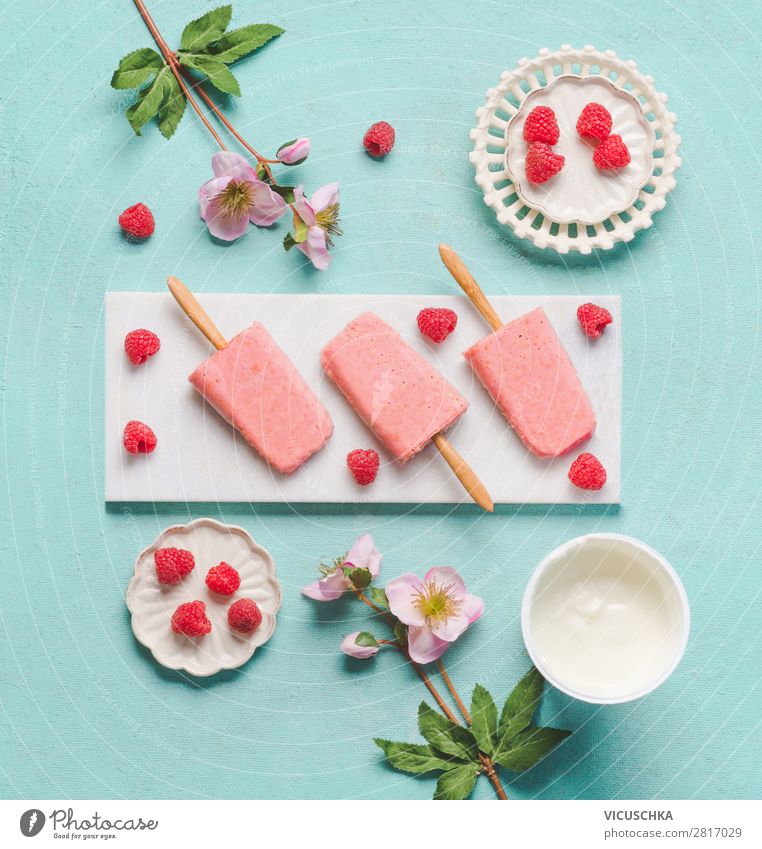 Hausgemachte Himbeeren Joghurt-Eis mit Zutaten auf hellblauem türkisem Hintergrund, Ansicht von oben, flach legen. Eis am Stiel. Sommer Essen. selbstgemacht