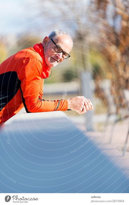 Senior-Läufer mit Sportbekleidung, die sich an einen Holzzaun lehnt. Lifestyle Erholung Joggen Telefon Mensch maskulin Mann Erwachsene Männlicher Senior 1