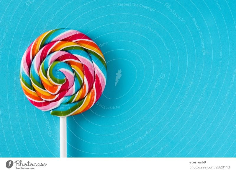 Bunter Lolli auf blauem Hintergrund. Draufsicht. Kopierbereich Lollipop Farbe mehrfarbig Zucker Süßwaren Bonbon süß geschmackvoll Hintergrund neutral