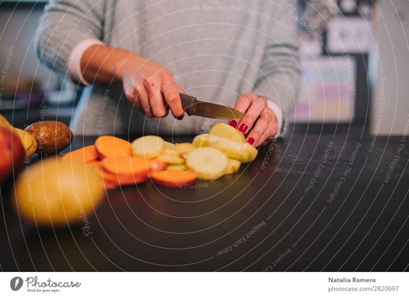 eine Person, die Kartoffeln und Süßkartoffeln in einer schönen Küche schneidet. Gemüse Essen Mittagessen Abendessen Diät Tisch Mensch Frau Erwachsene Hand Natur