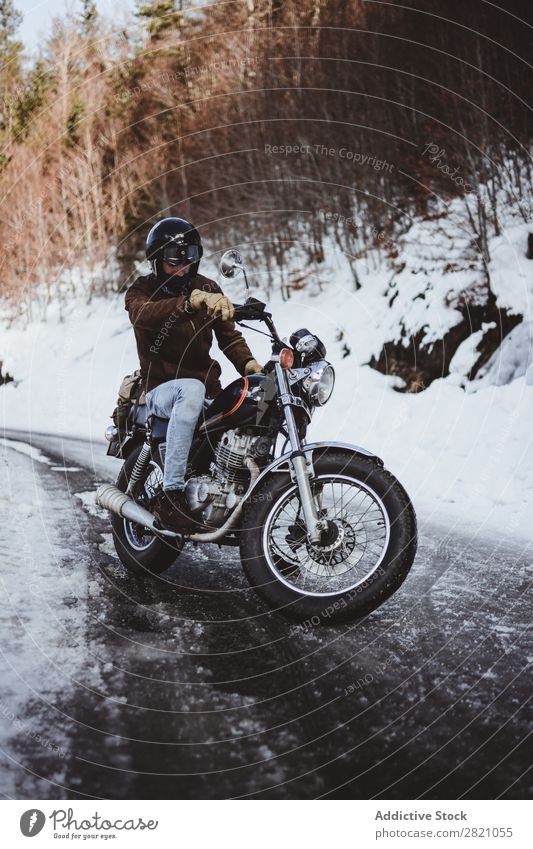 Mann fährt Motorrad auf verschneiter Straße Natur Fernweh Schnee Winter Körperhaltung Reisender selbstbewußt Wald Verkehr abgelegen Landschaft