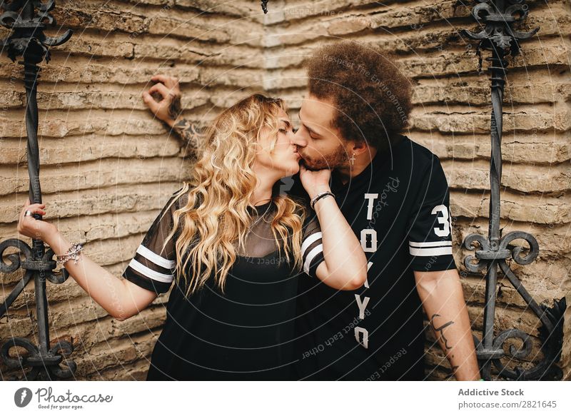 Küssendes Paar an der Steinmauer mit metallisch verzierten Stäben Schickimicki Liebe Partnerschaft Angebot Leidenschaft blond Haare & Frisuren Vollbart Mann