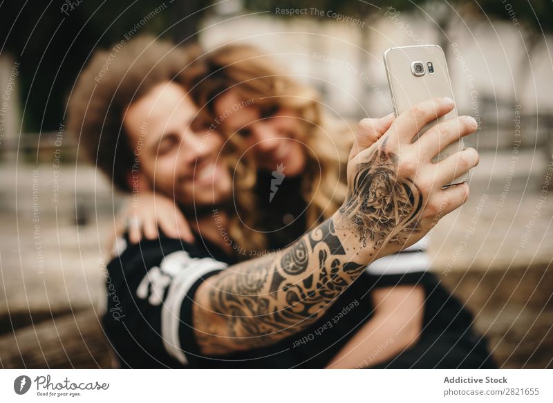 Paarweise Selfie über Smartphone herstellen PDA benutzend Technik & Technologie Fokus Lächeln Umarmen sitzen Außenaufnahme Arme Hand Tattoo alternativ