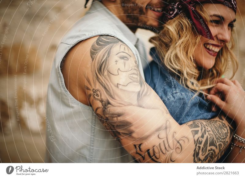 Freund, der seine lächelnde Freundin umarmt. Paar Lächeln Tattoo Arme Umarmen Profil Zahnfarbenes Lächeln Glück schön Gesicht Mädchen Nahaufnahme Körperteil