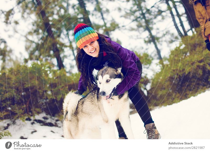 Lachende Frau beim Spielen mit dem Hund im Schnee Boxsport Spaß haben Zusammensein Haustier Säugetier weiß Natur heiter Freude Zufriedenheit kämpfen beißen