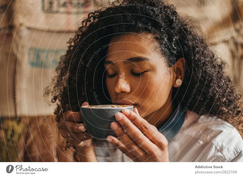 Frau trinkt eine Tasse Kaffee. schön urwüchsig schwarz Jugendliche Afrikanisch rühren Latte brünett attraktiv Mensch Beautyfotografie Erwachsene Stil niedlich