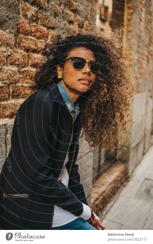 Stilvolle Frau an der Ziegelwand hübsch schön urwüchsig schwarz lockig Afrikanisch Jugendliche stehen Wand Backstein Straße Sonnenbrille brünett attraktiv