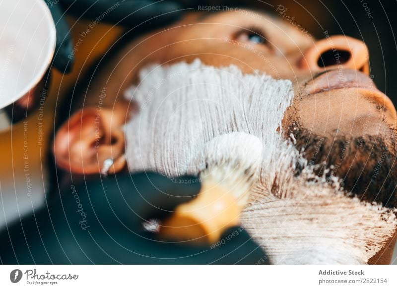 Friseur legt Schaum auf das Gesicht Friseursalon Kunde Haarkleid Behaarung Rasur Putten Salon schwarz Mann Jugendliche Klient Haare schneiden Haare & Frisuren