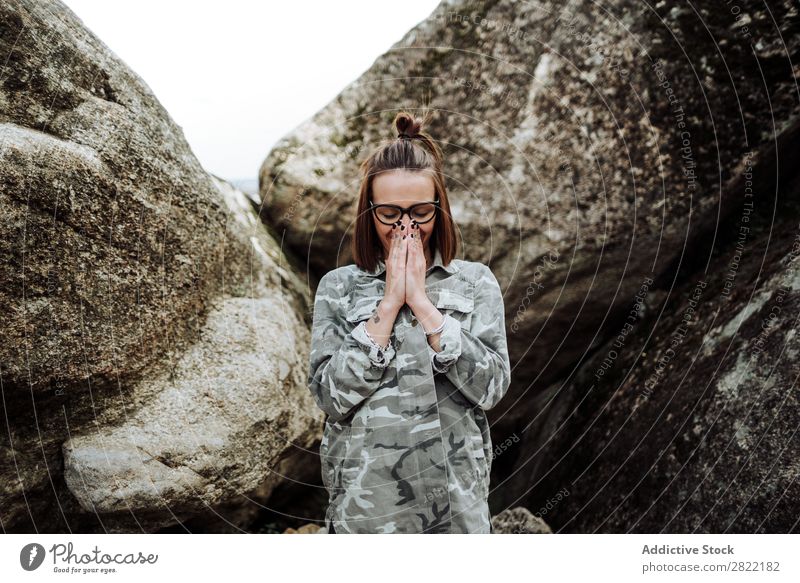 Frau in Gläsern betend auf Steine Stil Natur Felsen stehen Augen geschlossen Brillenträger attraktiv schön Jugendliche Mode Schickimicki hübsch Coolness