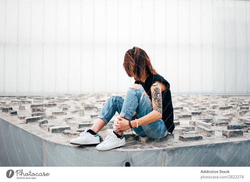 Nicht erkennbare tätowierte Frau auf dem Bürgersteig Stil Tattoo sitzen alt Relief Straßenbelag schön Jugendliche Mode Schickimicki hübsch Coolness