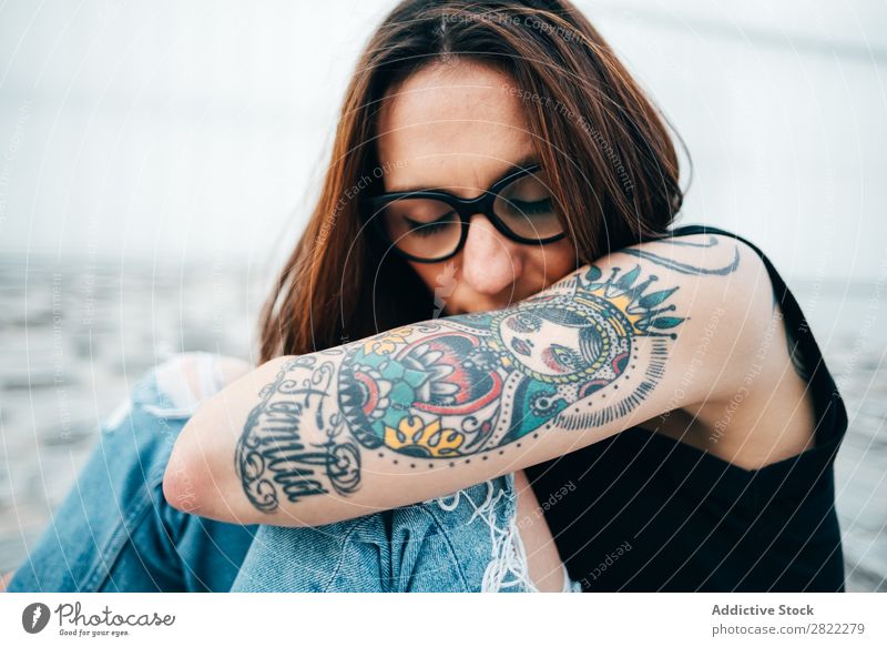 Frau mit Tattoos auf dem Bürgersteig sitzend Stil alt Straßenbelag Brillenträger Relief schön Jugendliche Mode Schickimicki hübsch Coolness Beautyfotografie