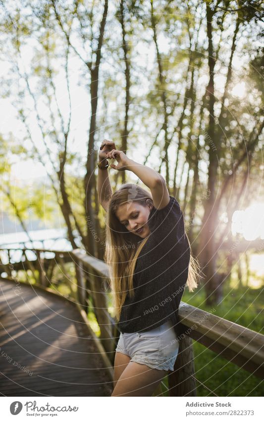 Junge Frau, die sich auf ein Brückengeländer stützt. Reling Natur Mensch hübsch schön Freizeit & Hobby Sommer Porträt Sonnenstrahlen Tag Baum Jugendliche