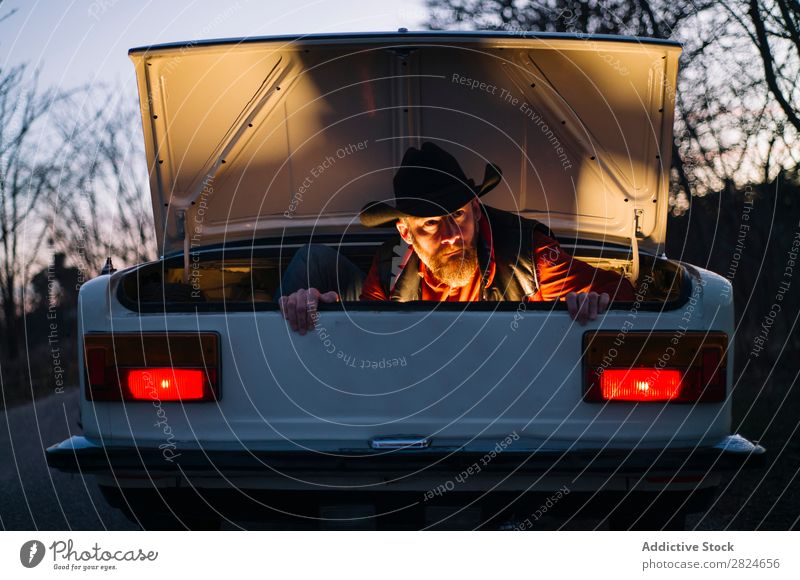 Mann im Kofferraum eines Oldtimers PKW altehrwürdig retro weiß Rüssel versteckend Hut Abend Fahrzeug klassisch Erwachsene Ferien & Urlaub & Reisen Mensch