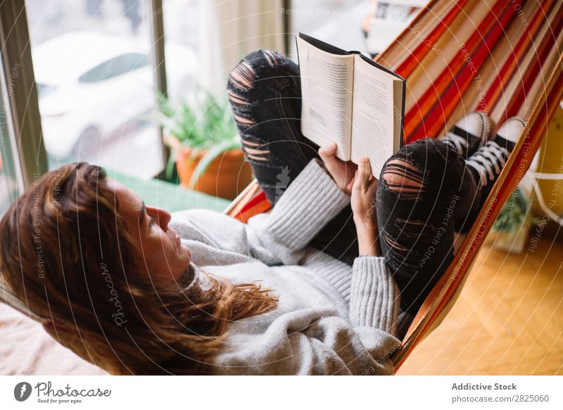 Fröhliche Frau liegend mit Buch heimwärts Erholung lügen Hängematte lesen heiter Literatur Lifestyle schön Raum Mensch lässig Erwachsene Haus Beautyfotografie