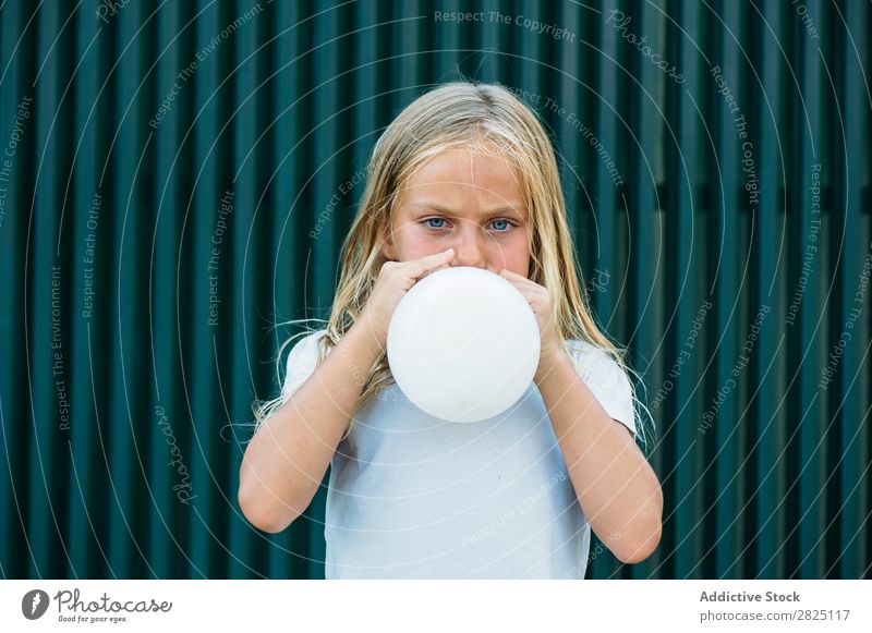 Mädchen bläst Ballon draußen. Luftballon wehen Körperhaltung ernst emotionslos Stadt Kindheit aufblasend Geburtstag Jugendliche Porträt Party Gesichtsbehandlung
