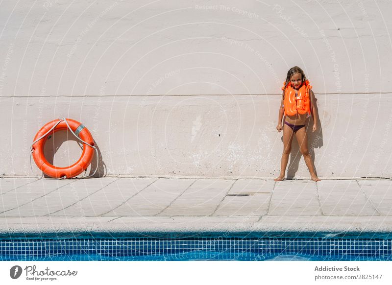 Fröhliches Mädchen, das in einer Schwimmweste posiert. Beckenrand Körperhaltung Sommer Badebekleidung aufblasbar Resort Ferien & Urlaub & Reisen Badeanzug