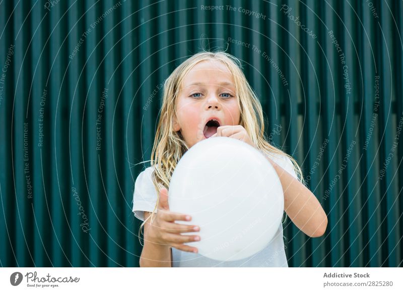 Mädchen bläst Ballon draußen. Luftballon wehen Körperhaltung ernst emotionslos Stadt Kindheit aufblasend Geburtstag Jugendliche Porträt Party Gesichtsbehandlung
