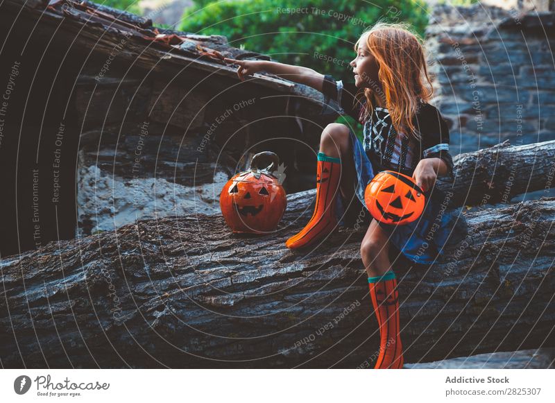 Fröhliches Kind im Kostüm, das auf einem Baum posiert. Mädchen Halloween Körperhaltung Feste & Feiern Tradition Zauberei u. Magie Ausdruck Süßwaren Bekleidung