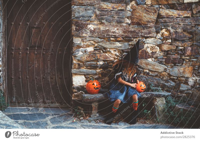 Kleines Mädchen in Hexenkostüm auf der Bank sitzend Halloween Süßwaren Hundefutter Ferien & Urlaub & Reisen Entertainment Festspiele Jahreszeiten Kostüm