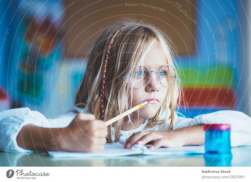 Nachdenkliches Mädchen beim Schreiben im Unterricht Klassenraum sitzen Schreibtisch schreibend Bleistift Zeichnung Denken Fürsorge gelangweilt niedlich Bildung