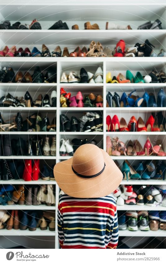 Person vor den Regalen mit verschiedenen Schuhen Mensch Rückansicht anonym unkenntlich Hut Ablage Schrank Mode Lager Stil Kleiderschrank Bekleidung heimwärts