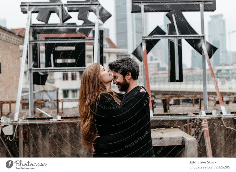 Ein Paar umarmt sich gegenseitig auf dem Dach. Mädchen küsst Typen Stirn Umarmen Dachterrasse Großstadt Liebe Aussicht Küssen Glück romantisch Zusammensein