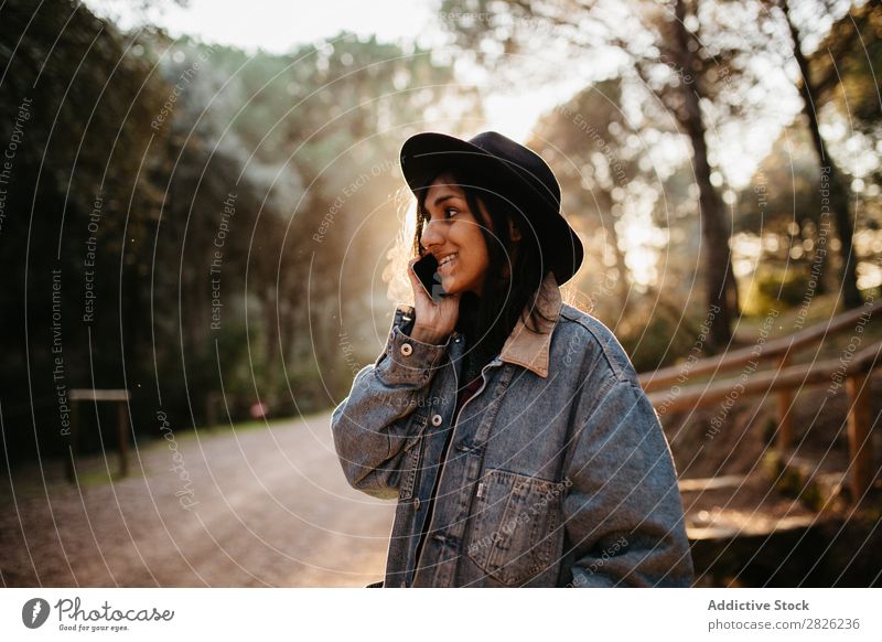 Indische Frau, die ein Telefon auf einer Landstraße benutzt. sprechen Tourist Wald Porträt Straße Technik & Technologie Herbst Jugendliche Sonnenuntergang