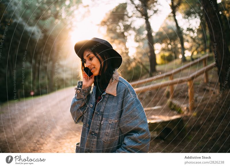 Indische Frau, die ein Telefon auf einer Landstraße benutzt. sprechen Tourist Wald Porträt Straße Technik & Technologie Herbst Jugendliche Sonnenuntergang