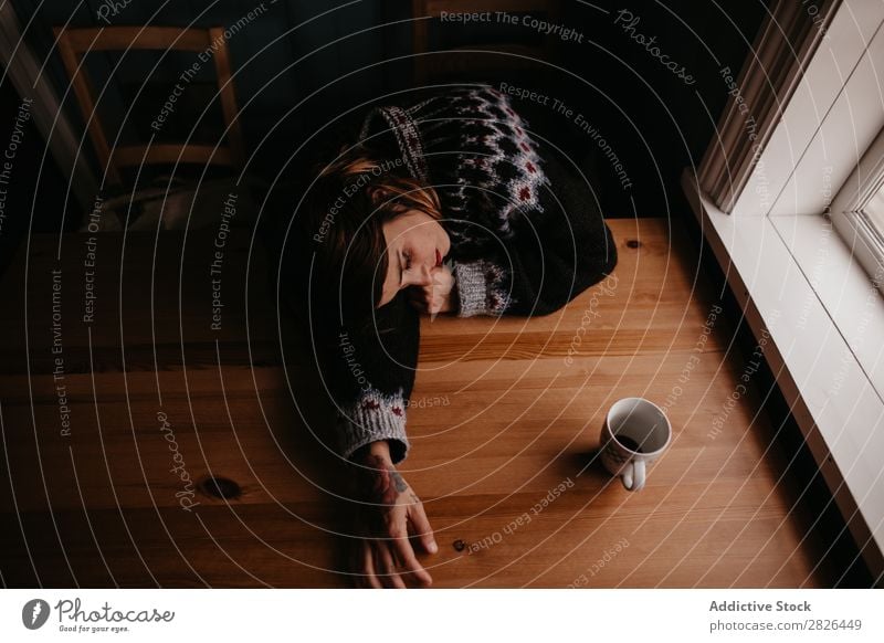 Frau auf dem Tisch liegend mit Tasse schlafen Island heimwärts Morgen erschöpft Müdigkeit träumen schlafend Stress Erholung Innenaufnahme aussruhen Becher