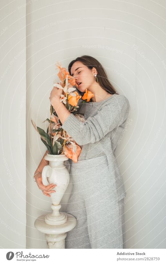 Sinnliche Frau, die Blumen umarmt. hübsch Jugendliche schön umarmend Orange Vase stehen genießen Augen geschlossen brünett attraktiv Mensch Beautyfotografie