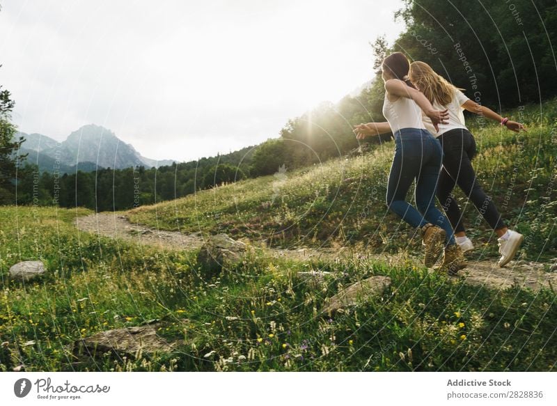 Fröhliche Frauen, die auf der Bergstraße laufen. Straße ländlich Freundschaft Rucksack Natur Mädchen Jugendliche schön Ferien & Urlaub & Reisen Tourismus