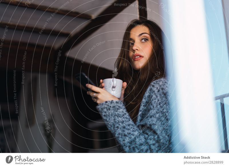 Schönes Modell mit Tasse Kaffee und Smartphone Frau heimwärts Kuscheln träumen Menschliches Gesicht Körperhaltung besinnlich Fürsorge Lifestyle Haus lässig