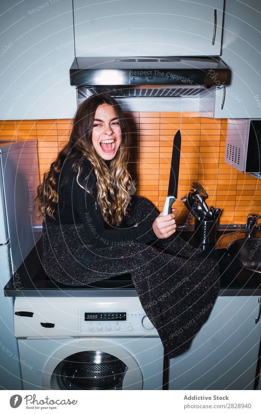 Ausdrucksstarke Frau, die mit dem Messer posiert. hübsch Körperhaltung expressiv sitzen Tisch gefährlich heimwärts Küche schön Lifestyle Jugendliche Mensch