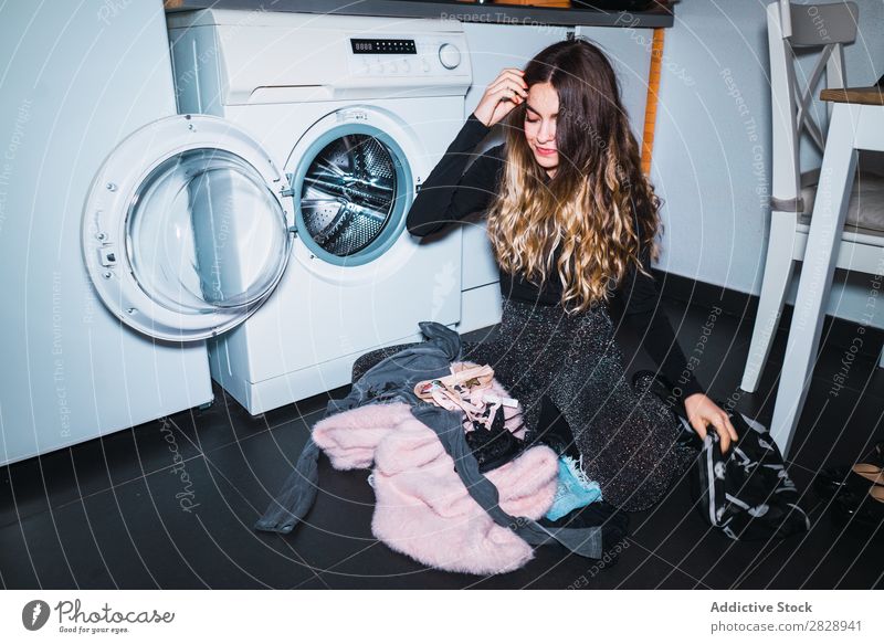 Frau, die an der Waschmaschine sitzt. hübsch Körperhaltung heimwärts Wäsche Maschine Bekleidung sitzen Küche Lächeln schön Lifestyle Jugendliche Mensch Glück