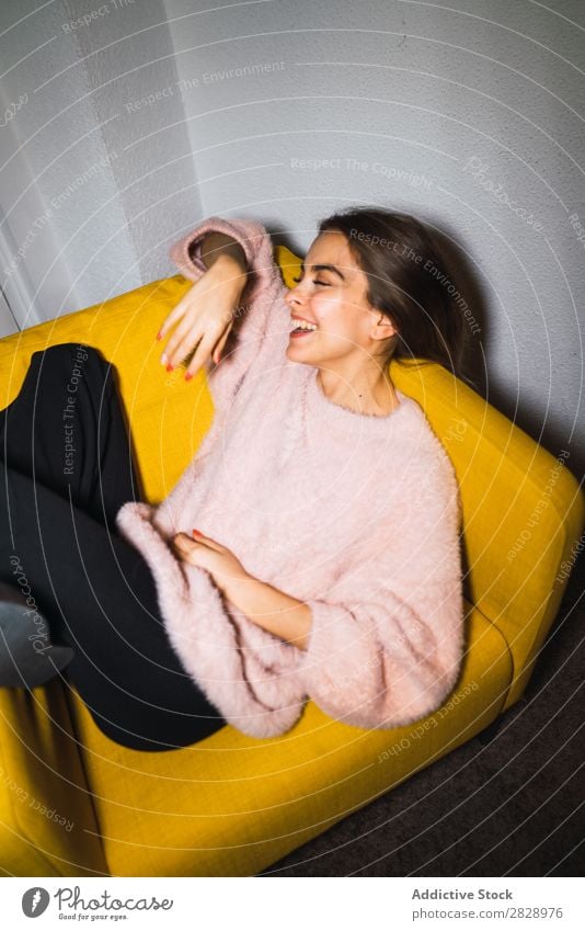 Junge Frau ruht sich auf einem Sessel aus. Jugendliche attraktiv heimwärts Pullover rosa sitzen lügen Glück expressiv Körperhaltung verführerisch schön Mensch