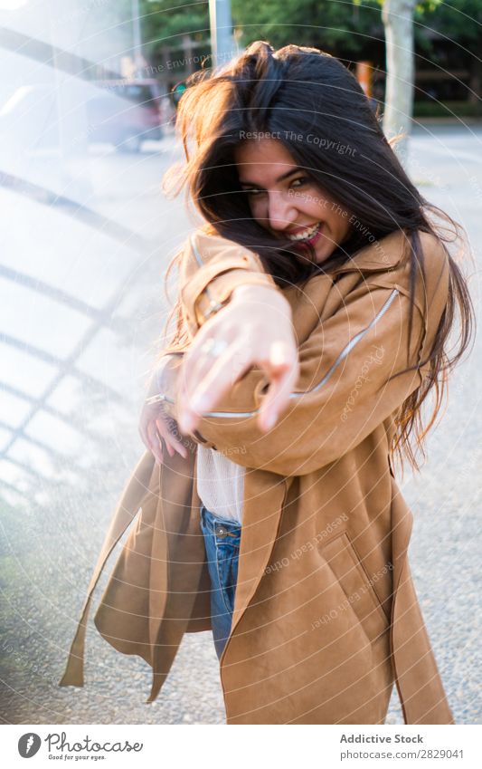 Junge hübsche Frau auf der Straße, die mit dem Finger auf die Kamera zeigt. Luftkuss heiter Kokette schön Körperhaltung Fröhlichkeit Flirten Erwachsene