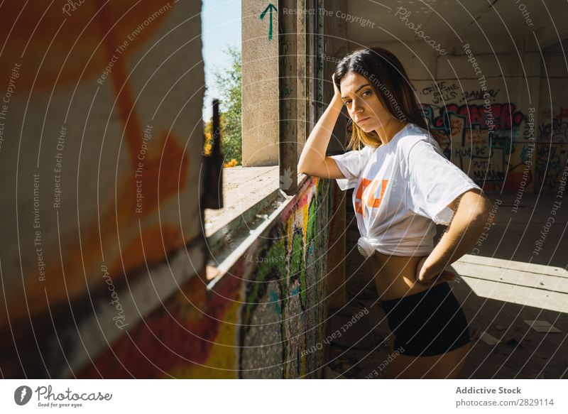 Lächelnde Frau in verlassenem Raum mit Graffiti heiter Körperhaltung Blick in die Kamera Glück Jugendliche schäbig mehrfarbig hübsch lässig Verlassen Gebäude