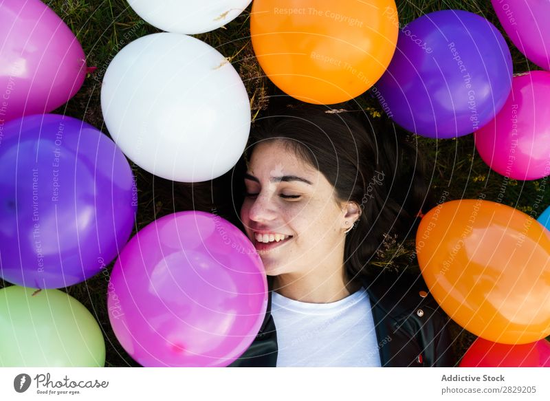Hübsche Frau, die in Luftballons liegt. Natur hübsch Körperhaltung lügen Gras Ballons Lächeln lachen Freiheit Freude schön Mensch Beautyfotografie Fröhlichkeit