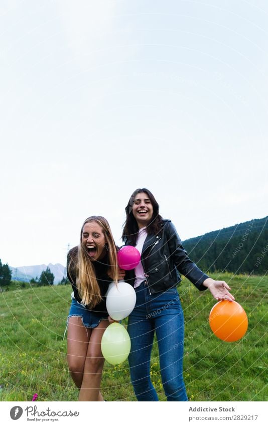 lachende Frauen, die Ballons aufwerfen. Natur Freundschaft Zusammensein Mensch kotzend Hände hoch hübsch Körperhaltung Freiheit Freude schön Beautyfotografie