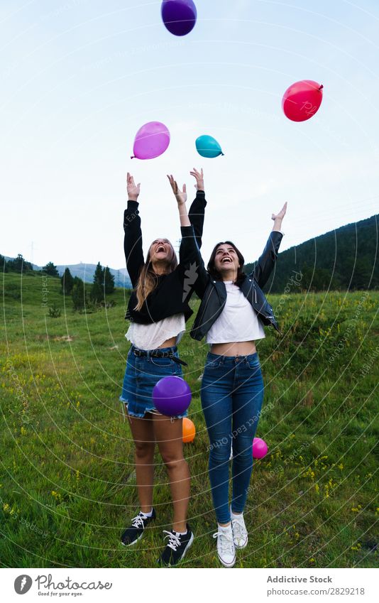 lachende Frauen, die Ballons aufwerfen. Natur Freundschaft Zusammensein Mensch kotzend Hände hoch hübsch Körperhaltung Freiheit Freude schön Beautyfotografie