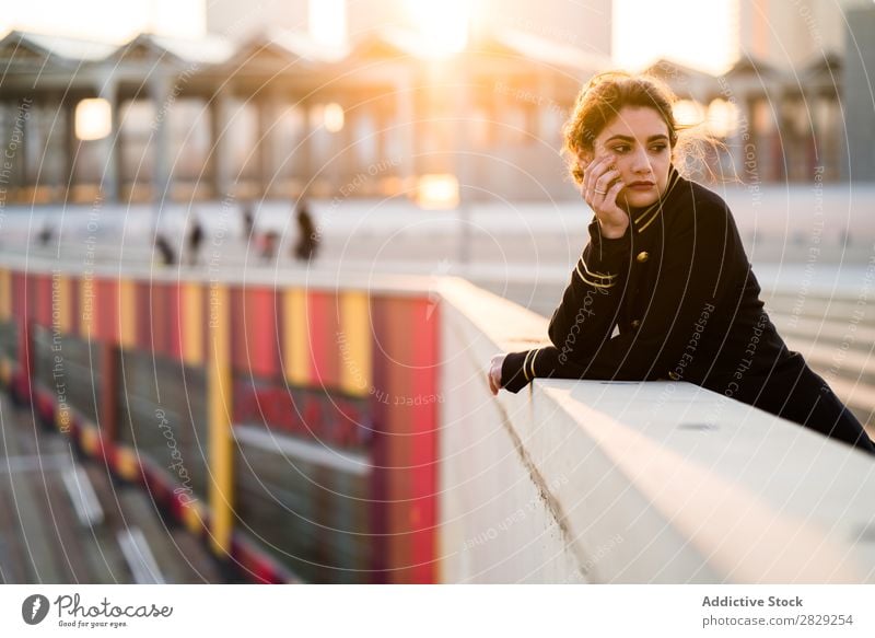 Frau im Sonnenuntergangslicht am Handlauf stehend Haltekopf Geländer selbstbewusst in die Kamera schauen lässig Kleidung stylisch ernst jung Behaarung schön
