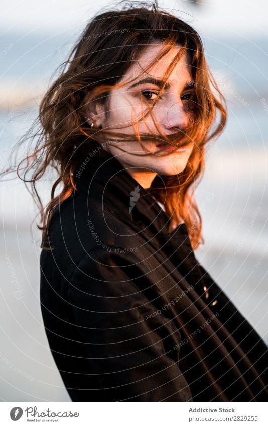 Porträt einer ernsthaften jungen Frau, die mit fliegenden Haaren in die Kamera schaut. Sonnenuntergang Behaarung selbstbewusst in die Kamera schauen lässig