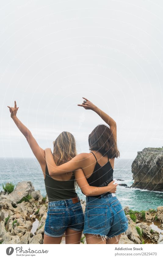 Frauen mit erhobenen Armen, die auf der Klippe stehen. Meer schön Felsen Sommer Natur Ferien & Urlaub & Reisen Wasser Landschaft Jugendliche blau Lifestyle