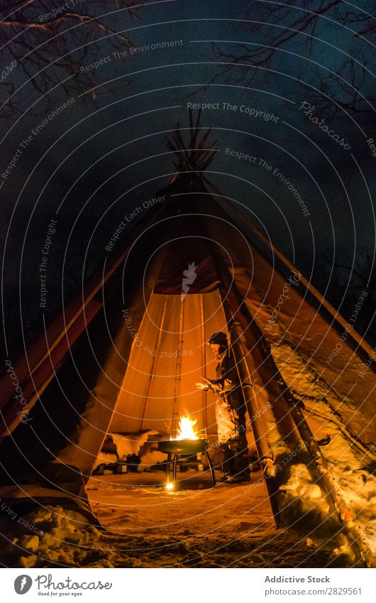 Mann wärmt sich im Zelt auf Winter Natur kalt Norden bedeckt Licht Nacht Freudenfeuer Mensch Erwärmung stehen Tourist Reisender Wald Schnee Jahreszeiten weiß