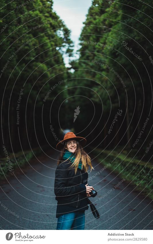 Lächelnde Frau mit Kamera im Wald Fotograf grün Natur Fotokamera Hut hübsch Jugendliche Straße Asphalt Umwelt Blick in die Kamera natürlich Jahreszeiten Pflanze
