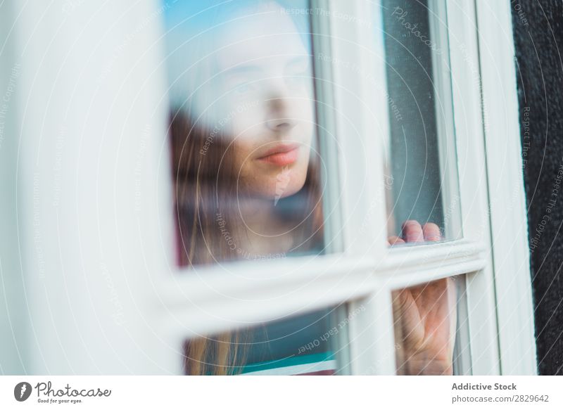 Träumendes Mädchen, das durchs Fenster wegblickt. Frau träumen Beautyfotografie Porträt schön besinnlich genießen Reflexion & Spiegelung Denken Erholung